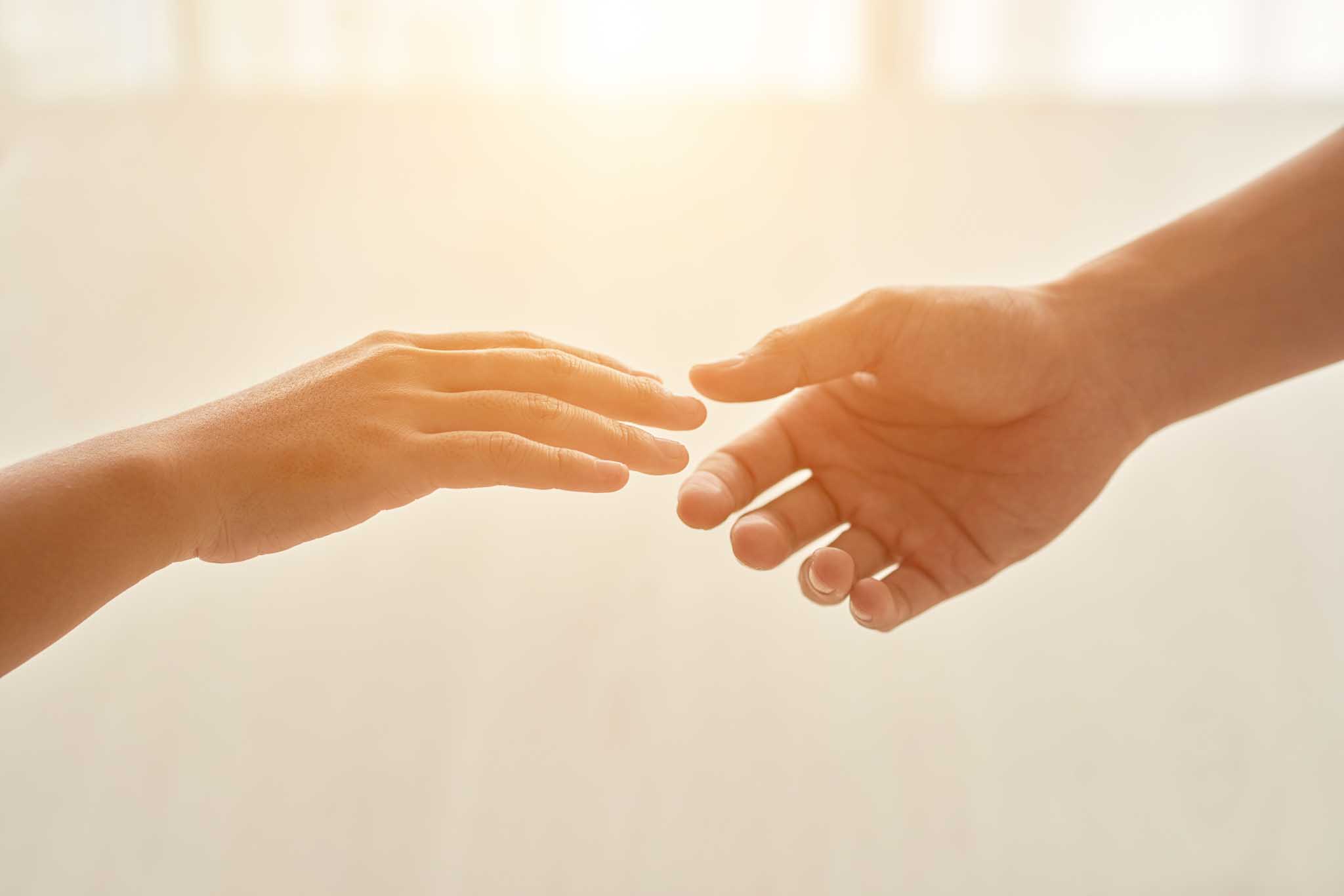 Two hands about to touch as helping.